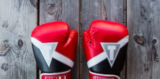 pair of red-and-black Title training gloves on grey wooden plank