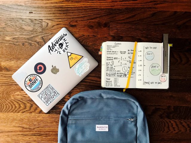 Photo by Matt Ragland flat lay photography of blue backpack beside book and silver MacBook