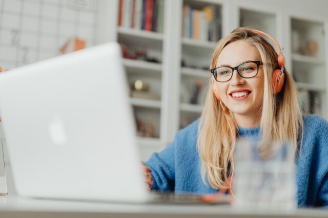 Woman Smiling While Using a Laptop