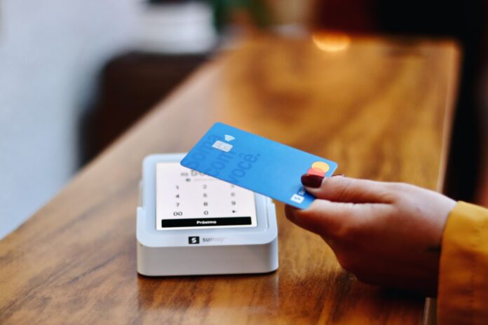Photo by Nathana Rebouças a person holding a credit card in front of a machine