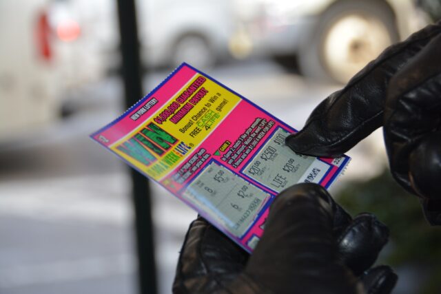 Photo by Ryan Brooklyn a person in black gloves holding a ticket