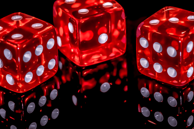 Three red dices on a black surface
