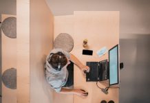 woman in blue shirt sitting on chair using laptop computer